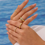Close-up of hands with gold rings against a blue water background