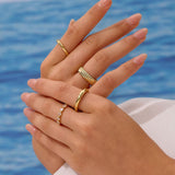 Close-up of hands with gold rings against a blue water background