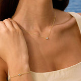 Woman wearing a gold necklace and bracelet with a blue ocean background
