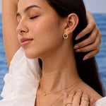 Woman wearing gold jewelry with a blurred ocean background