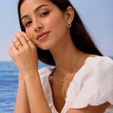 Woman wearing gold jewelry with a blue ocean background
