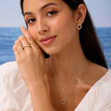Woman wearing gold jewelry with a blue ocean background