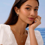 Woman wearing gold jewelry with a blurred ocean background