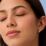 Close-up of a woman wearing a gold earring against a blue background