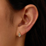 Close-up of a person wearing a teardrop-shaped earring with a blurred background