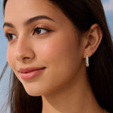 Close-up of a woman wearing a diamond earring with a blurred natural background