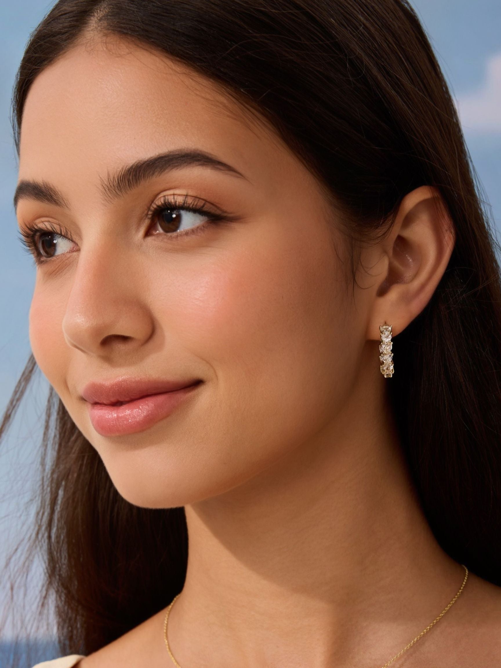 Close-up of a woman wearing a diamond earring with a blurred natural background