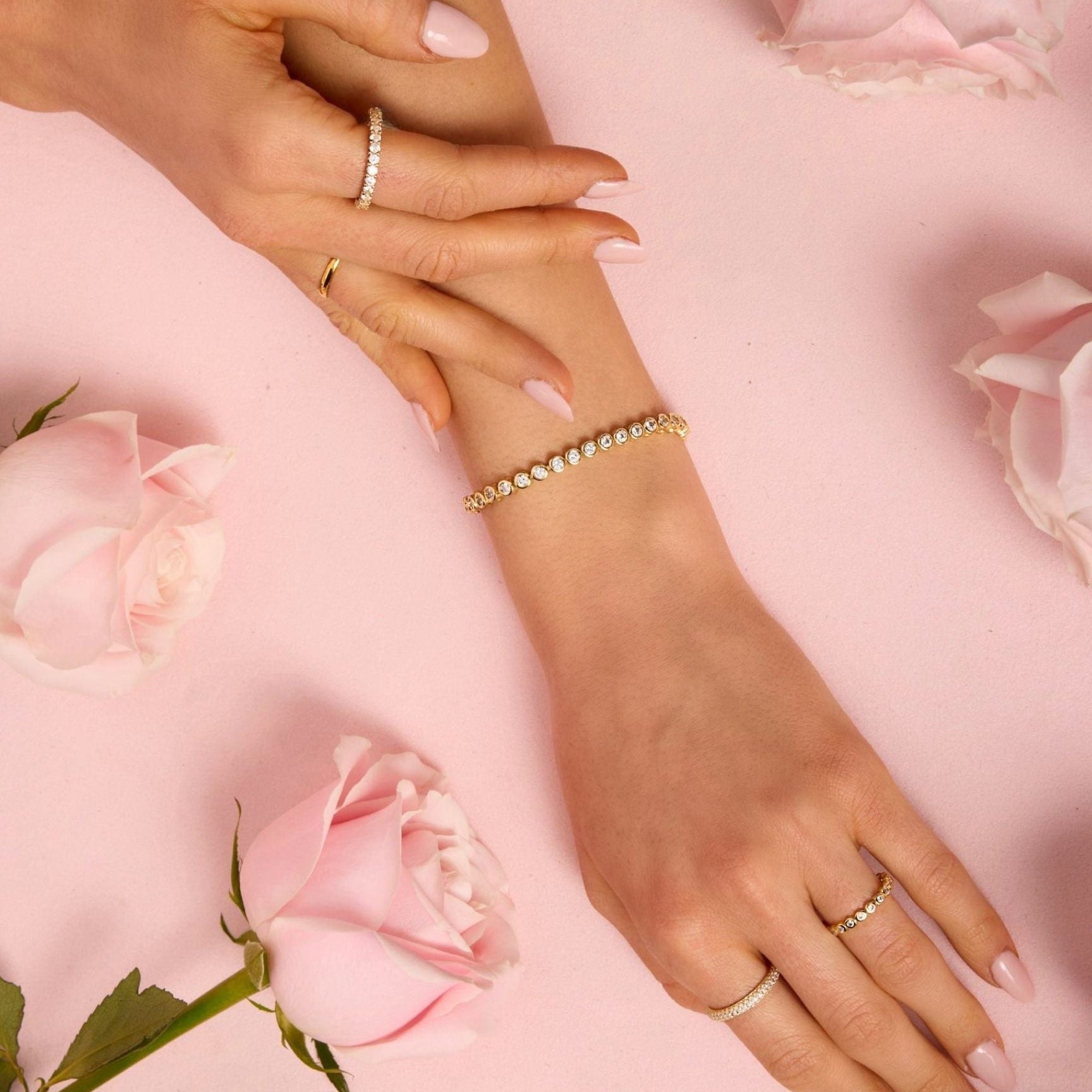 Close-up of hands with jewelry on a pink floral background