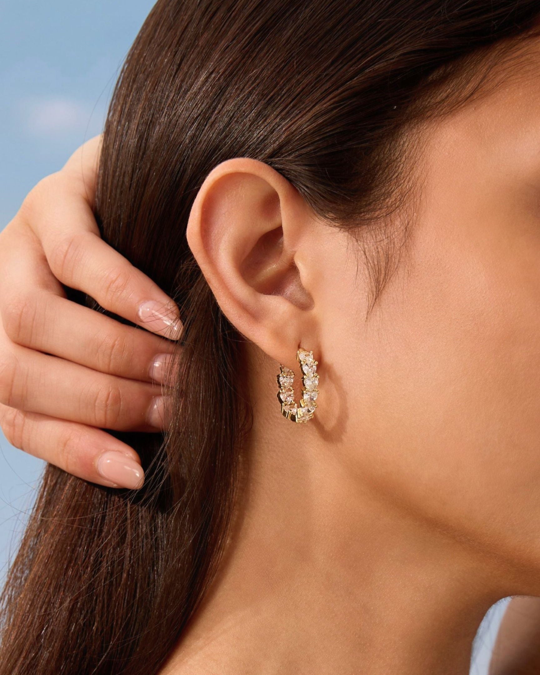 Close-up of a person wearing a gold hoop earring with a blurred background