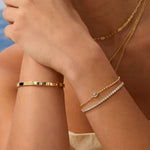 Close-up of a person's arm wearing gold bracelets with a blurred background