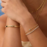 Close-up of a person's arm wearing gold bracelets with a blurred background