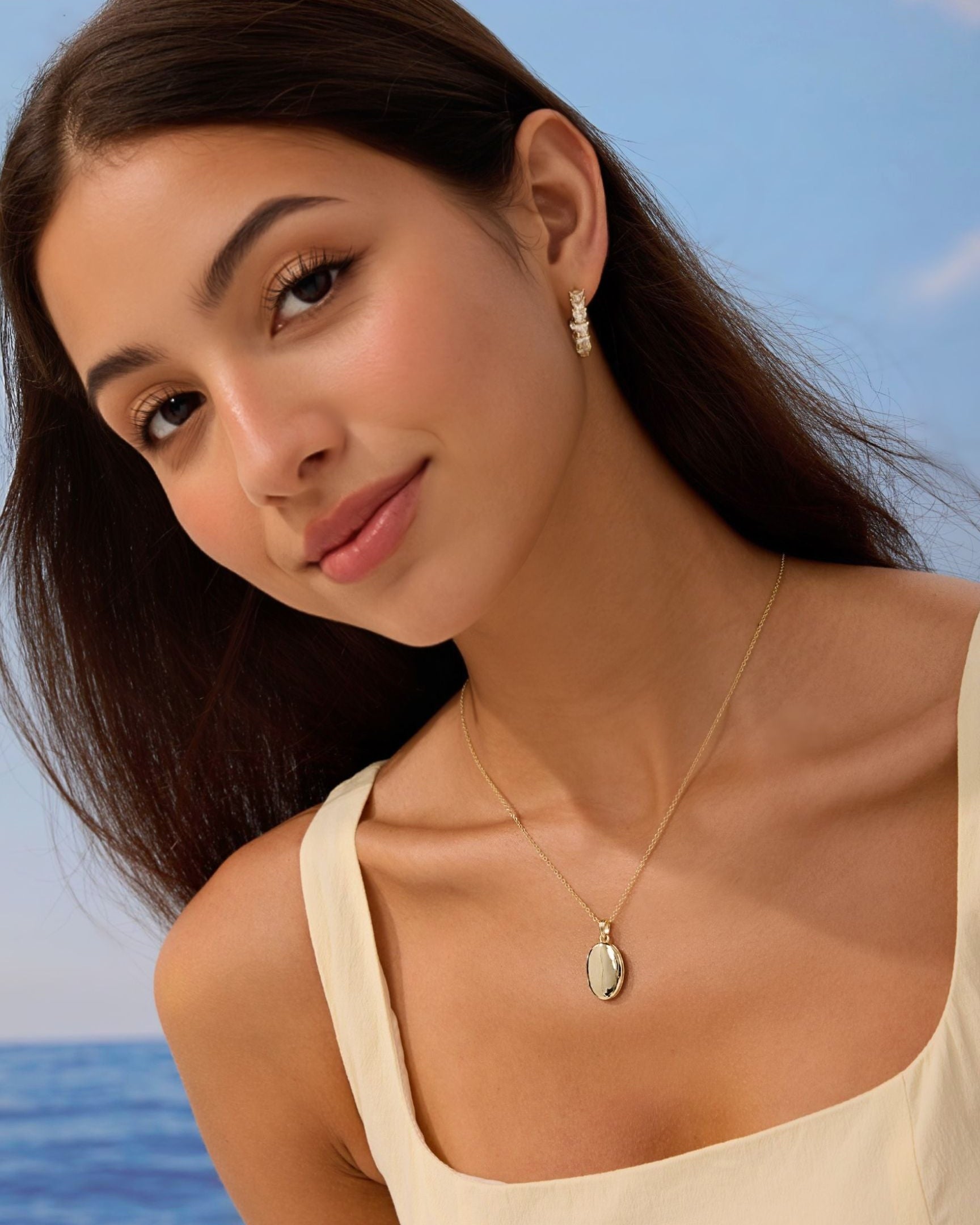 Woman wearing a necklace with a pendant against a blue sky and ocean background