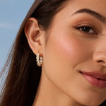 Close-up of a woman wearing diamond hoop earrings with a clear blue sky background