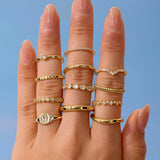 Hand wearing multiple gold rings with a blue background